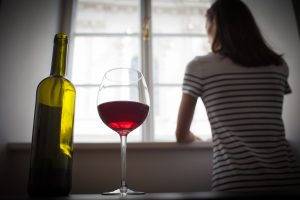 Imatge d'arxiu d'una dona mirant per la finestra i una botella de vi.